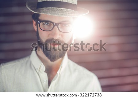 Portrait of confident man wearing hat and eyeglasses against wall