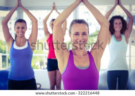 Cheerful women in fitness studio with hands joined overhead while standing
