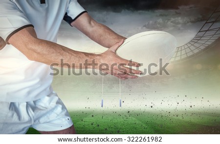 Midsection of rugby player holding the ball against rugby stadium