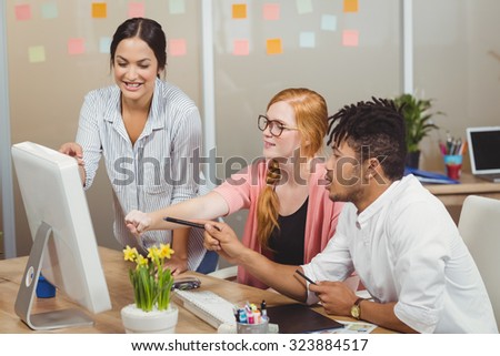 Smiling business people pointing towards computer at desk during meeting