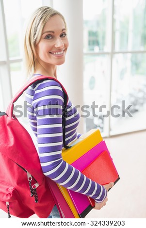 Close-up portrait of young female student with backpack and books in college