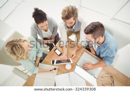 Overhead view of business people with digital tablet while sitting at desk in office