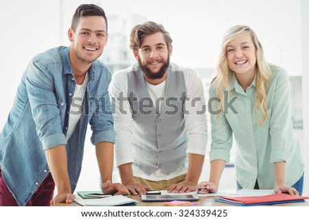 Portrait of smiling business professionals while standing at desk