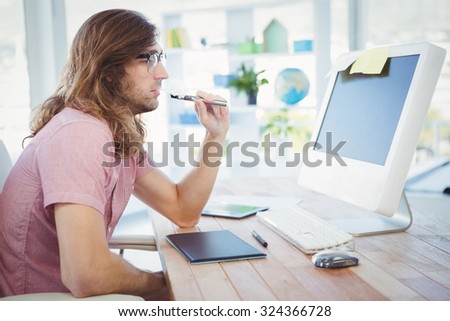Side view of hipster smoking electronic cigarette at computer desk in office