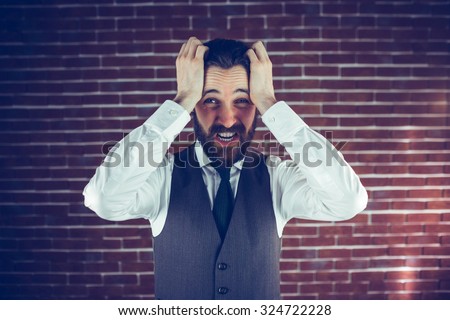 Portrait angry man with head in hands against brick wall