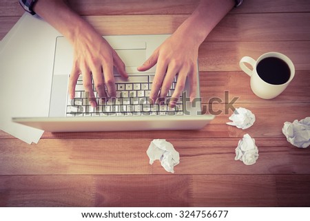 High angle view of man working on laptop by black coffee at desk in office