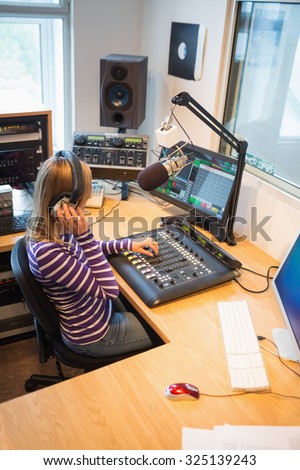 High angle view of female radio host operating sound mixer in studio