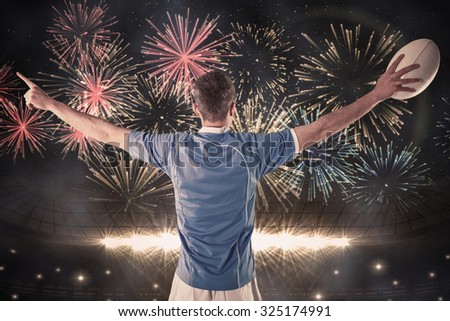 Rugby player about to throw a rugby ball against fireworks exploding over football stadium