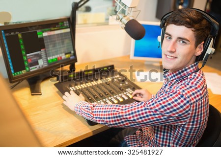 Portrait of radio host operating sound mixer on table at studio