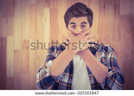Portrait of shocked man covering mouth against wooden wall