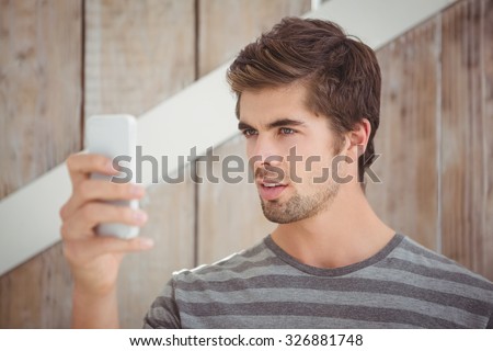 Man looking at mobile phone while standing against wooden wall