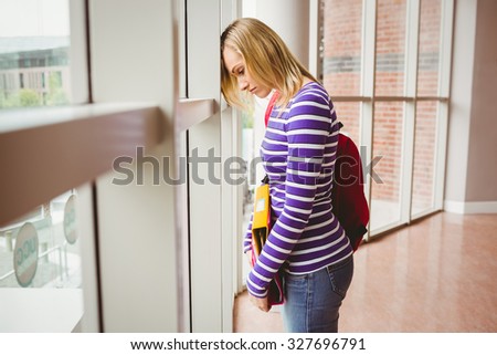 Side view of sad female student by window in college