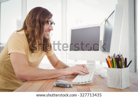 Happy hipster working on computer at desk in office