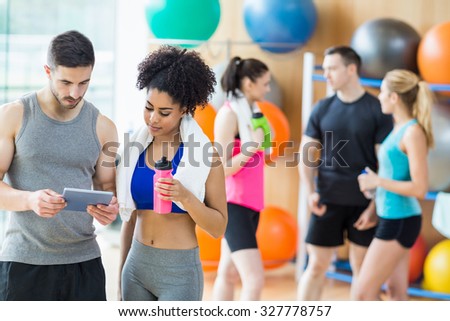 Client and trainer looking at tablet pc at the gym