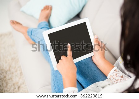 Over shoulder view of a woman using tablet on the couch at home - Stock ...