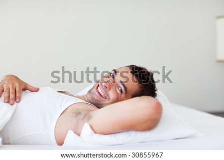 Handsome man lying in his bed smiling