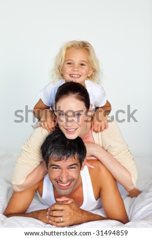 Father, mother and daughter playing together in bed