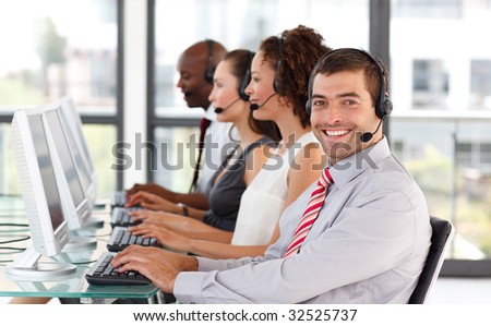 Smiling businessman working in a call center with his colleagues