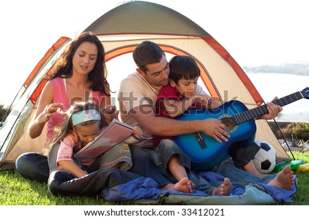 Family playing a guitar in a tent