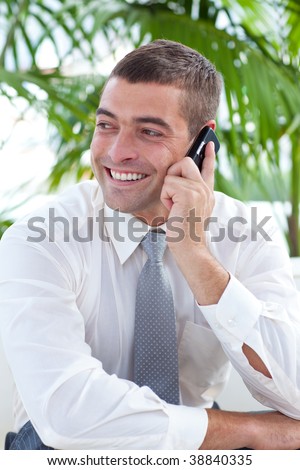 Businessman sitting on sofa and talking on phone in workplace