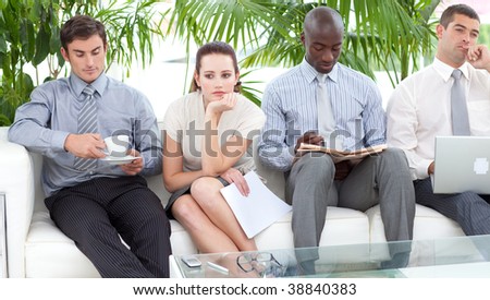 Bored multi-ethnic business people sitting on a sofa waiting for an interview