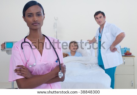 Serious attractive nurse with doctor and patient in the background