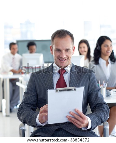 Attractive male manager writing notes in a call center