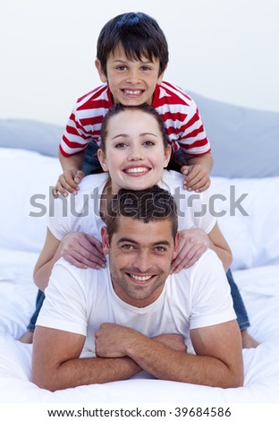 Happy parents and son playing in bed together