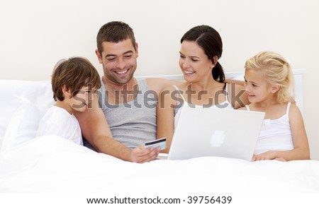 Family buying online with a laptop in bed
