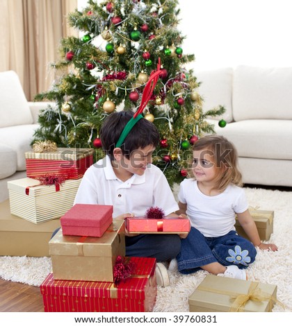 Happy brother and sister looking at Christmas gifts at home