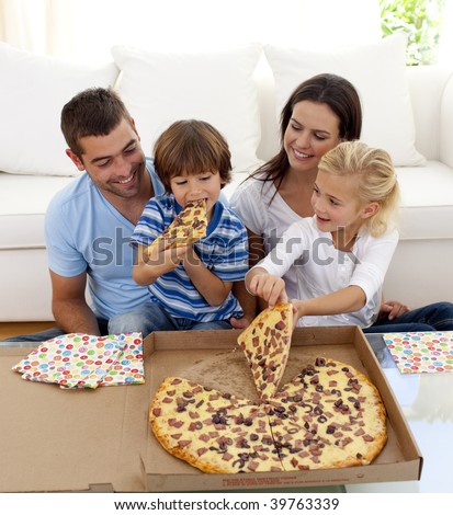 Happy young family eating pizza in living-room all together