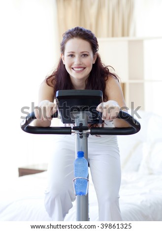 Woman doing spinning bike in her bedroom at home