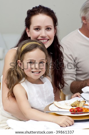 Mother and daughter having dinner with their family at home