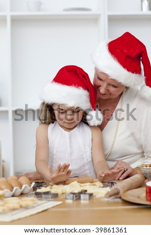 Smiling grandmother and little girl baking Christmas cakes in the kitchen