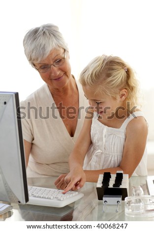 Granddaughter explaining her grandmother how to use a computer at home