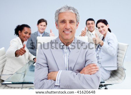 Happy businessman leading his happy team with thumbs up in the office