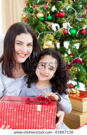 Smiling mother and daughter playing with Christmas gifts