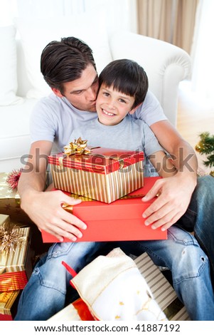 Father kissing his son after giving him a Christmas gift in the living-room