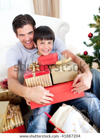 Happy father and son holding Christmas presents at home