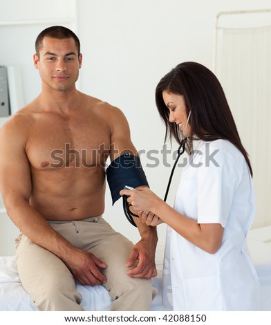 Smiling doctor checking the blood pressure of a patient in the hospital