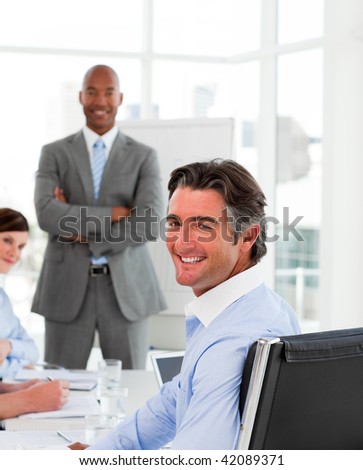 Businessmen in a meeting with their team smiling at the camera
