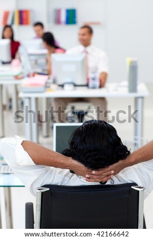 Businessman leaning back on a chair in front of his team in the office