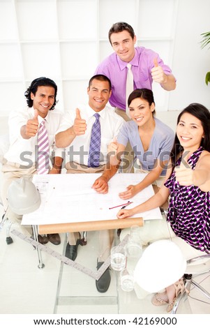 A group of architects with thumbs up in a meeting. Concept of success.