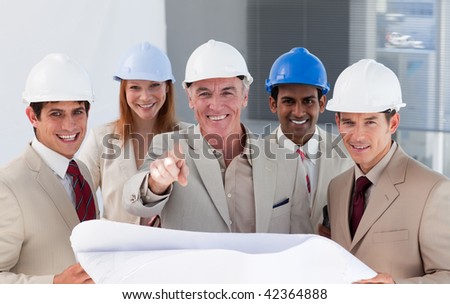 A group of smiling architects studying blueprints in a building