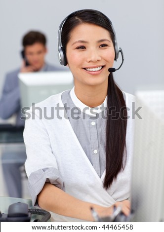 Smiling businesswoman with headset on at a computer in the office
