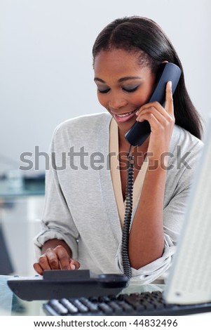 Assertive ethnic businesswoman talking on a phone in the office