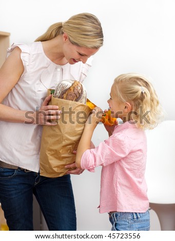 Smiling mother and her Little girl unpacking grocery bag in the kitchen