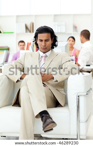 Serious manager sitting in an armchair in front of his team in the office