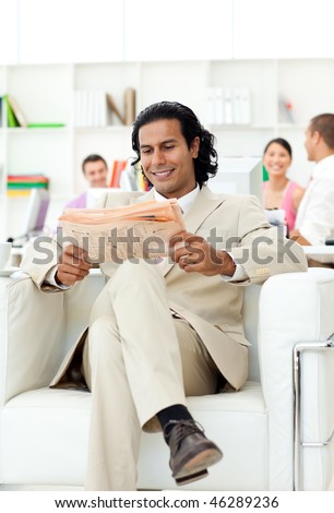 Smiling manager reading a newspaper in the office