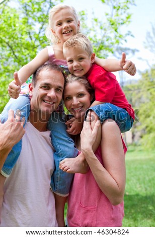 Cheerful parents giving their children piggy-back ride in a park